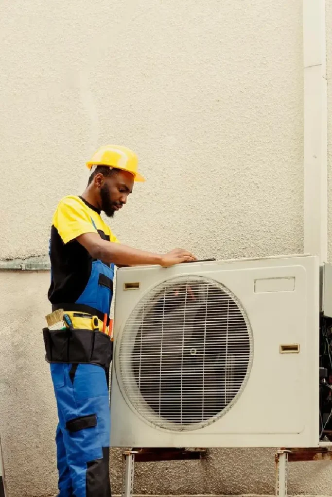 Technician inspecting outdoor air conditioning unit.