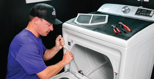 Technician repairing dryer vent inside laundry room